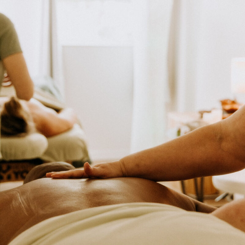 Massage therapist applying gentle pressure to a client's back in a calm, softly lit spa setting for wellness services