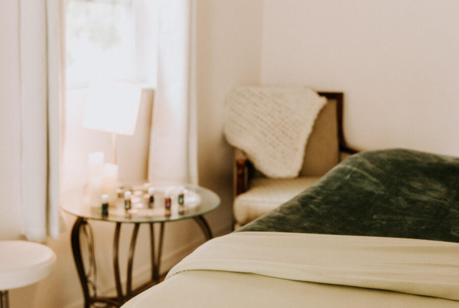 Peaceful massage room with a massage table, cushioned stool, and soft natural lighting.