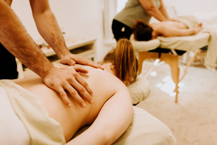 Two people receiving back massages in spa.