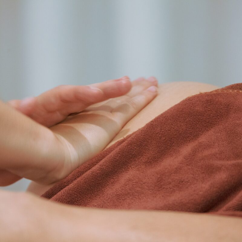 Hand on pregnant belly covered with towel Lymphatic Drainage Massage