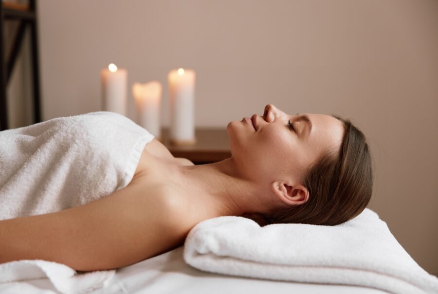 Woman relaxing at a spa with candles lit.