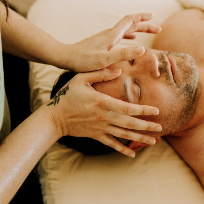 Therapist giving facial massage to man.