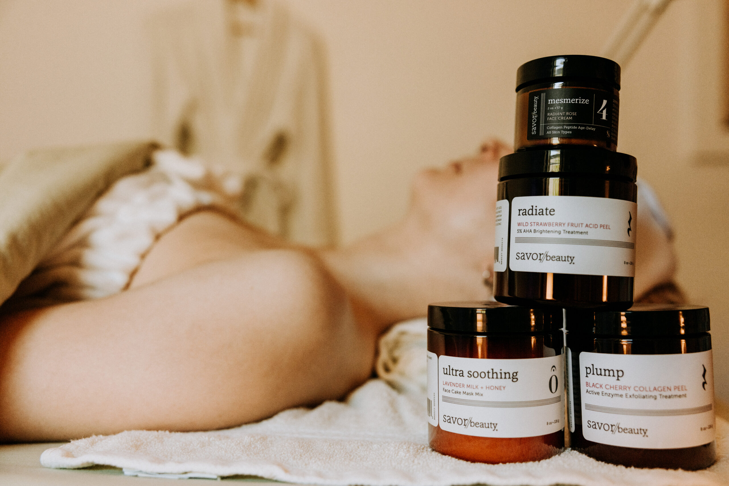 Skincare products stacked on bed in spa setting.